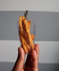 A hand holding a small clear plastic cup with three pieces of chin-chin